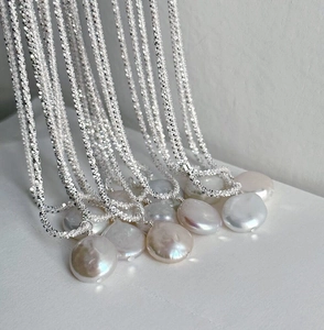 Detailed view of silver shimmering chains and diverse baroque pearl pendants with iridescence