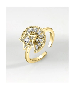 Macro detail of golden spinning star and moon ring with clear zircon inlay and beaded texture