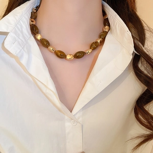Detail of amber resin and gold beads necklace styled on model with a white shirt