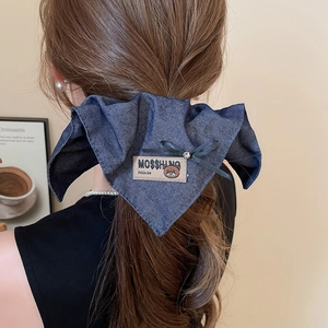 Detailed view of denim fabric hair claw with bear patch and bow on a low ponytail