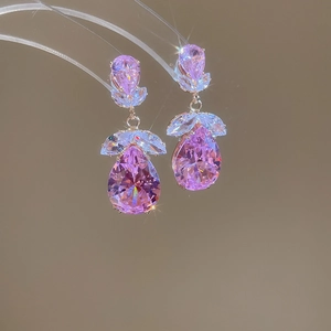 Gros plan de boucles d'oreilles en zircon rose en forme de goutte et détails floraux