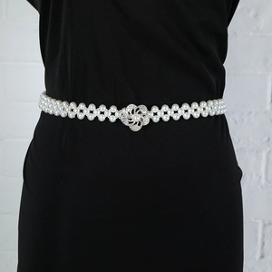Detail of double-row pearl waist chain with a silver floral rhinestone buckle on black dress