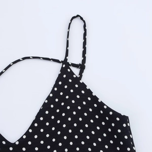 Dettaglio dello scollo a V e delle spalline sottili di un abito nero a pois