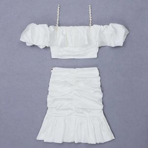 Detailed view of white satin two-piece set featuring pearl straps and ruffled mini skirt