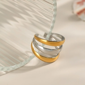 Three-layer gold and silver mixed color minimalist open ring on a striped glass cup