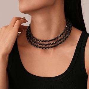 Detailed close-up of a three-layer black beaded choker necklace on a model