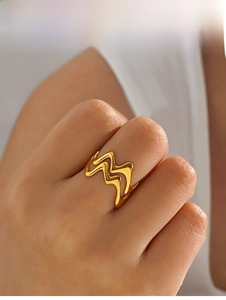Detail shot of wavy 18K gold plated stainless steel ring on model hand with golden glow