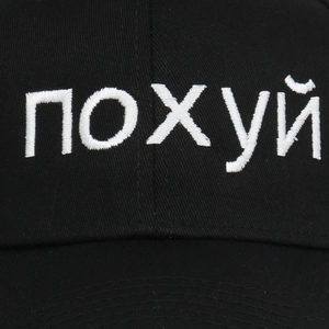 Close-up of white Russian embroidery on black cotton twill baseball cap texture
