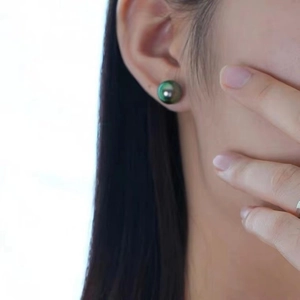 Close-up of a 10mm peacock green Tahitian pearl earring worn on a woman's ear