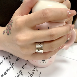 Detailed view of silver titanium steel ring with engraved geometric X pattern texture