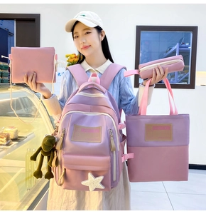 Pink and purple nylon school backpack four-piece set shown by model in a retail shop