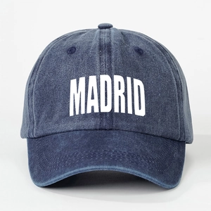 Detailed view of the MADRID printed text on the washed navy blue denim baseball cap