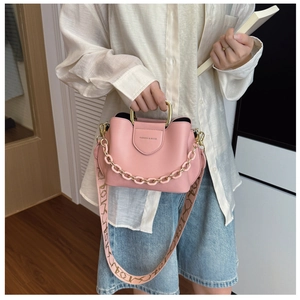 Detail of light pink leather bag with wide vintage patterned shoulder strap and gold handle
