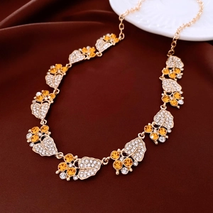 Close-up of vintage leaf pendant necklace with orange and white zircons on dark silk