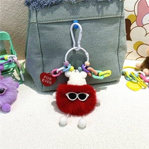 Détail du monstre en peluche rouge avec lunettes et bonnet tricoté sur un sac en jean