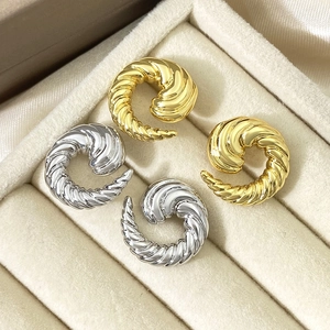 Detailed view of gold and silver twisted spiral hoop earrings in a velvet display tray