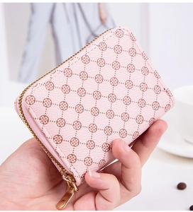 Pink mini coin purse with floral pattern and gold zipper held in hand for size context