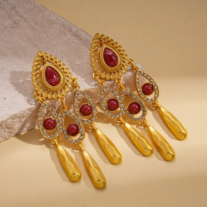Vue détaillée de boucles d'oreilles vintage avec résine rouge et pompons dorés
