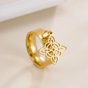 Detail of a wide gold stainless steel ring with a hanging Celtic knot cutout pendant