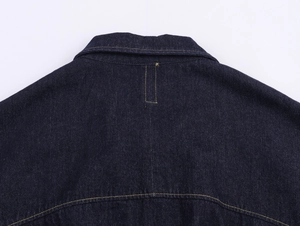 Détail de la structure du col et texture du tissu denim épais sur une veste bleu foncé