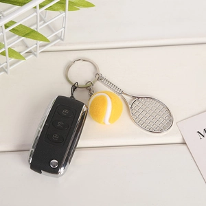 Detail view of silver mini tennis racket and ball keychain attached to a car key fob