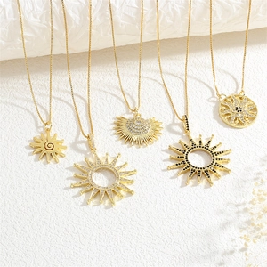 Detail of five gold sunburst pendants with sparkling zircons on white fabric