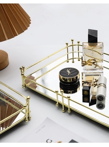 Détail d'un plateau miroir en métal doré avec un cadre décoratif à perles