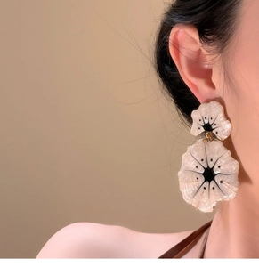 Macro view of double-layered ginkgo flower earrings with marble texture on female model