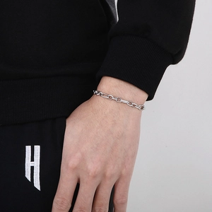 Detailed close-up of a minimalist silver stainless steel oval link chain bracelet on wrist