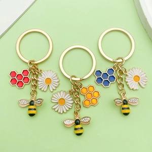 Detailed shot of bee and hexagon honeycomb pendants in red orange and blue on gold keychains