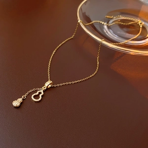 Vue détaillée du collier en acier doré avec pendentifs gourde et glands en zircon