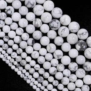 Natural white turquoise beads in various sizes arranged diagonally on black background