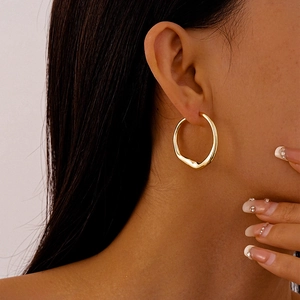 Close-up of minimalist irregular gold circle earrings worn by a model for a stylish look