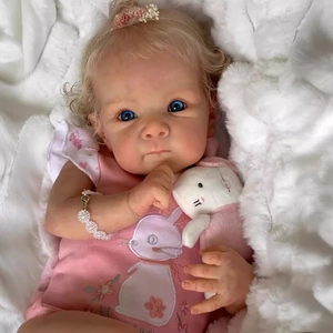 18-inch Bettie reborn baby doll with blonde hair and pink bunny onesie on white blanket