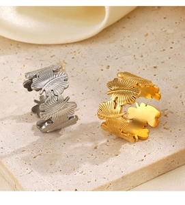 Macro shot of gold and silver leaf-textured stainless steel rings on a stone surface