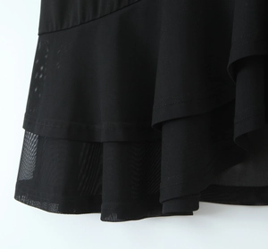 Detail view of black chiffon dress featuring layered ruffled hem and mesh stitching