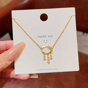 Close-up of golden cloud pendant necklace with sparkling tassel fringe on display card