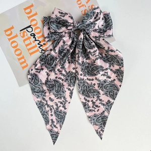 Detailed view of pink paisley print satin bow hair clip with long elegant ribbons