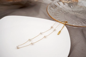 Close-up of a minimalist gold chain necklace with delicate freshwater pearls on silk