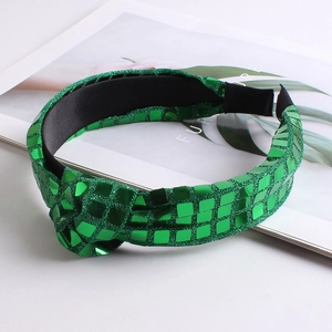 Detailed view of a green sequined knotted headband on a professional white background