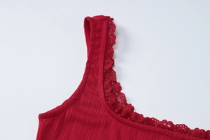 Gros plan d'un caraco rouge en maille côtelée avec bordure en dentelle sur l'encolure carrée