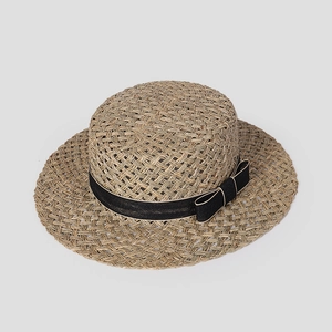 Detail of hand-woven natural straw boater hat featuring a stylish black ribbon bow