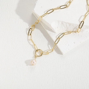 Close-up of golden paperclip chain necklace featuring a round freshwater pearl pendant