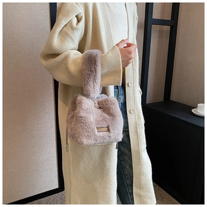 Detailed shot of pink faux fur bucket bag with drawstring and golden metal plate