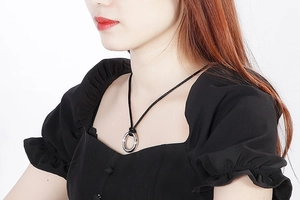 Macro view of textured silver round pendant with black velvet cord necklace on model