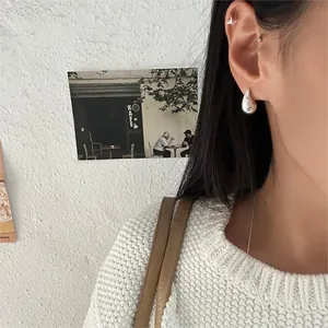 Close-up of minimalist S925 sterling silver water drop earrings worn on ear model