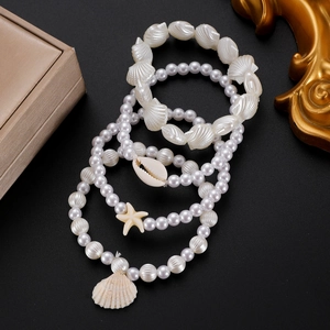 Dettaglio del set di quattro braccialetti di perle con conchiglie e stelle marine