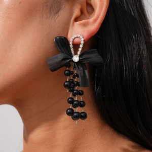 Close-up of black chiffon bow earrings with crystal accents and long beaded tassels