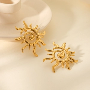 Detailed macro view of spiral sun stud earrings with textured gold metal finish