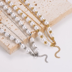 Elegant layered pearl necklace with gold and silver metal chains on natural stone